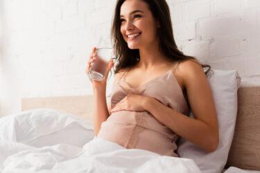 笑顔で水を飲む妊婦